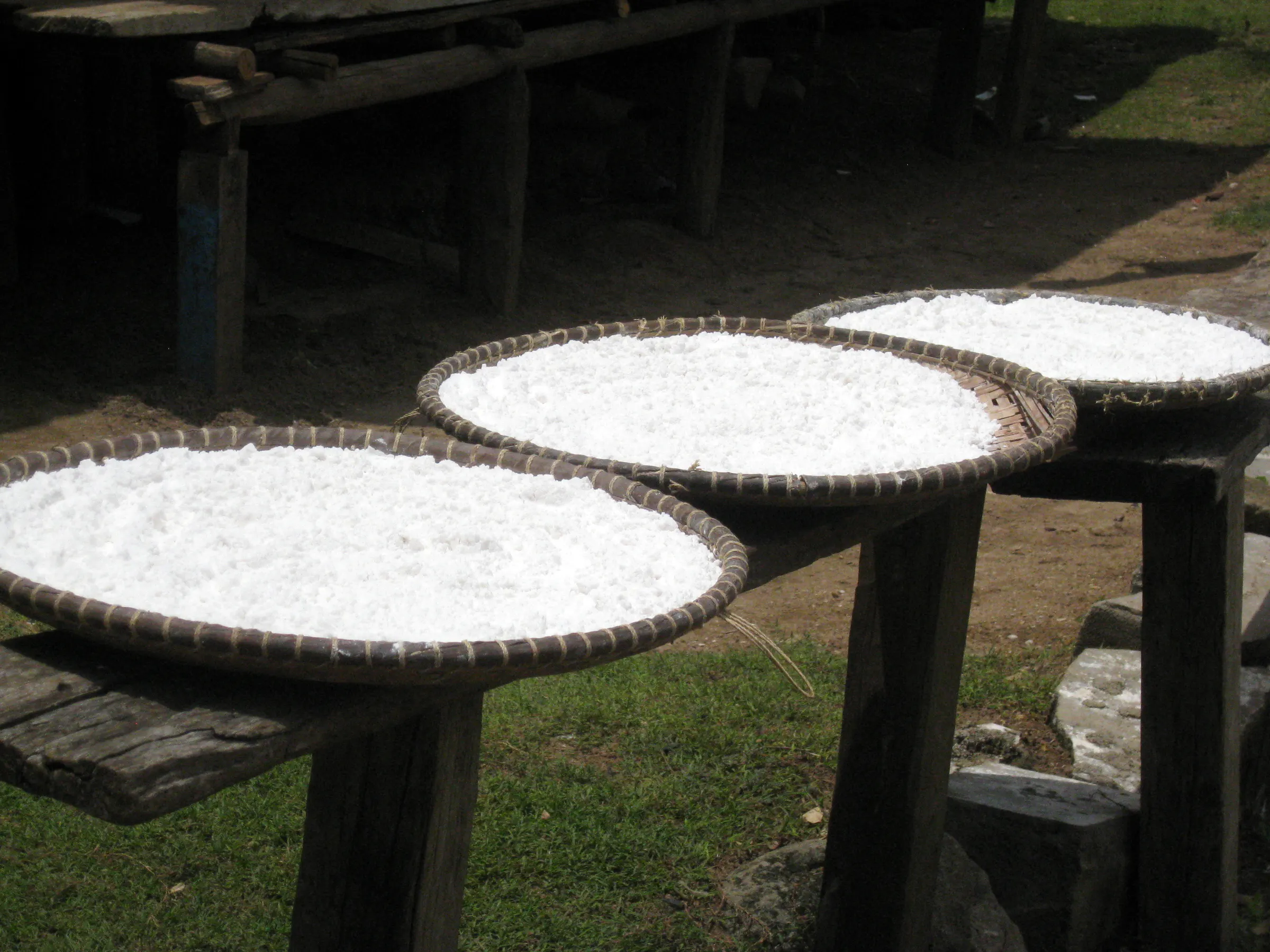 White rice spread on woven trays to dry in the sun